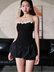 Woman wearing a black dress with white lace trim in an indoor setting.