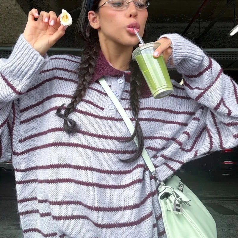 Person in a striped sweater drinking from a green cup outdoors