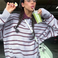 Person in a striped sweater drinking from a green cup outdoors