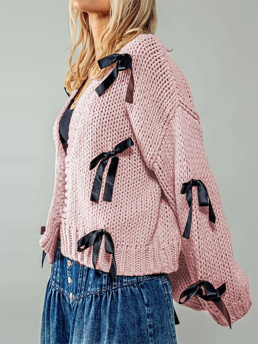 Pink knitted cardigan with black ribbons worn by a person- side