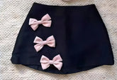 Black skirt with three pink bows on a textured surface