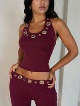 Woman wearing a burgundy outfit with decorative buttons on a plain background