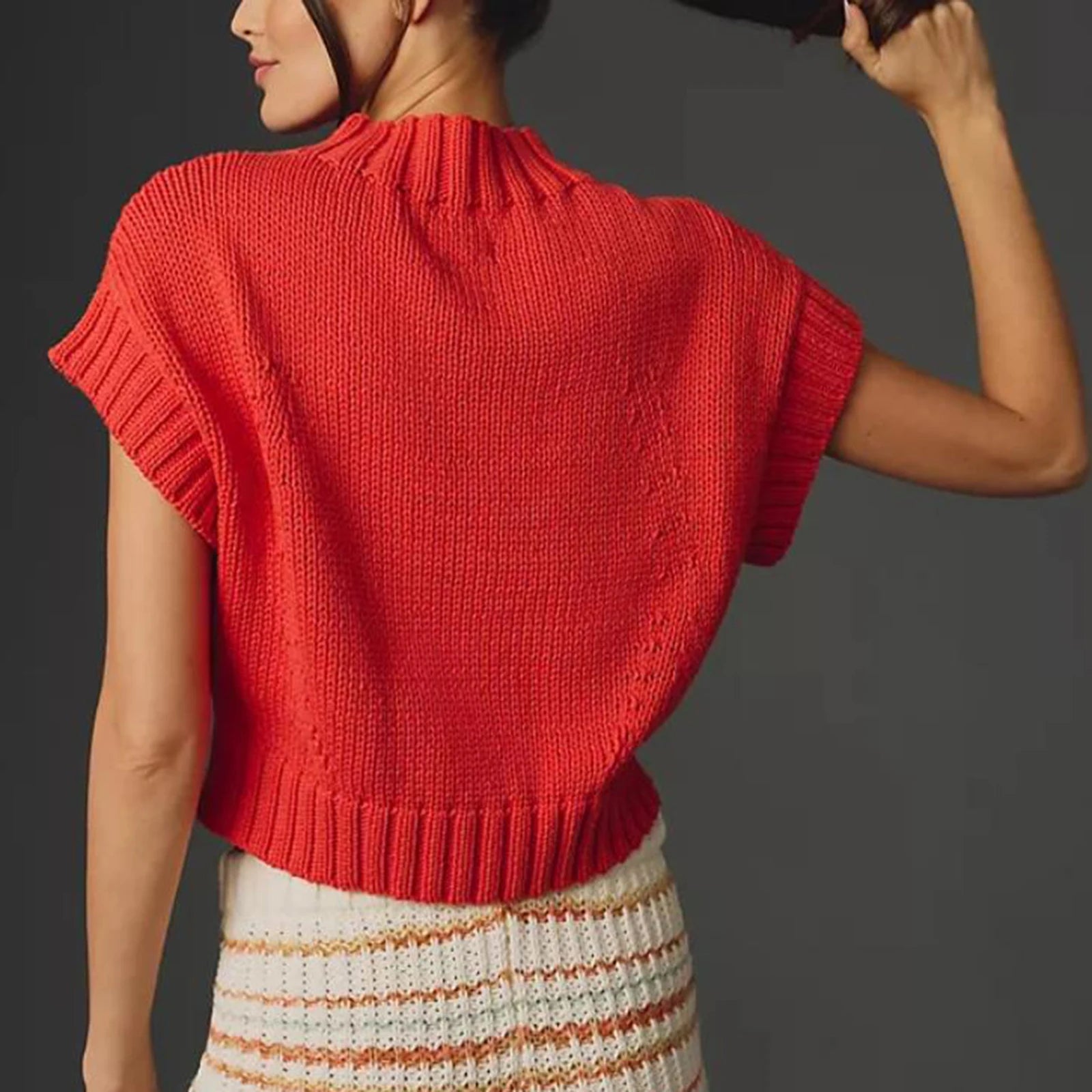 Red knitted top worn by a person on a dark background