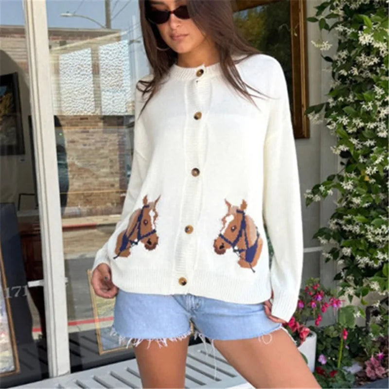 Woman wearing a white cardigan with horse designs outdoors.