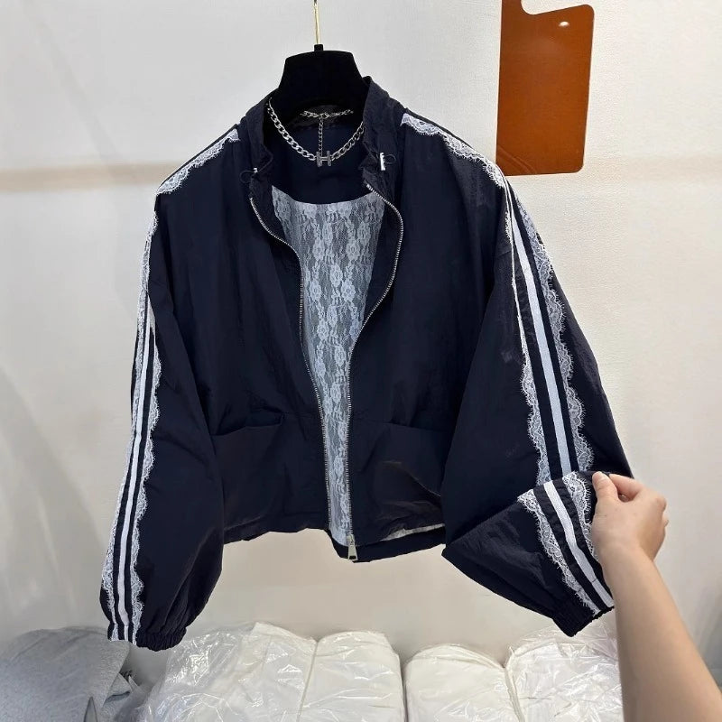 Black jacket with white stripes on sleeves held by a hand against a white background