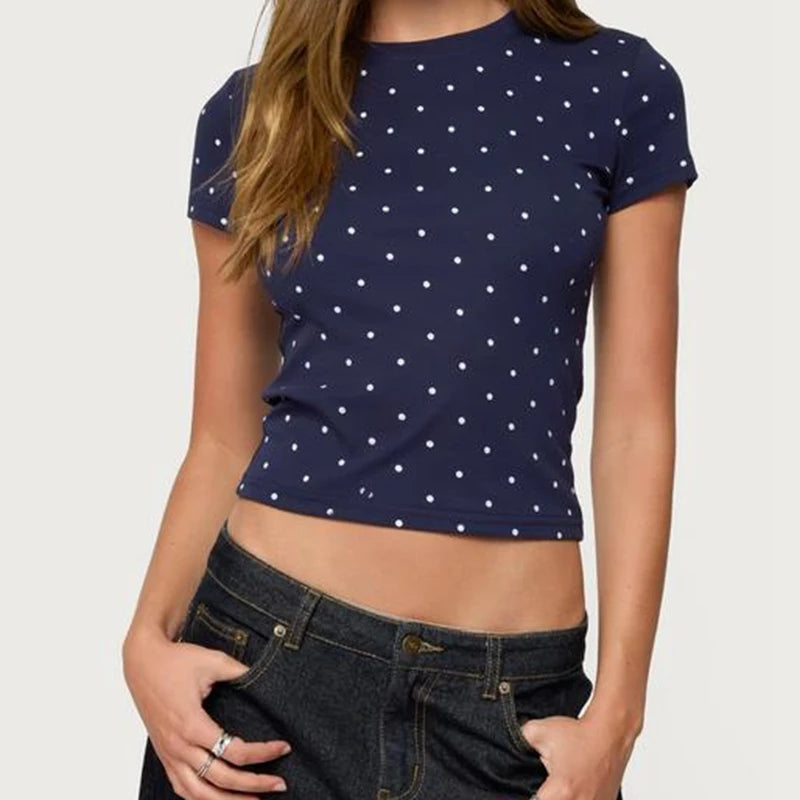 Person wearing a navy blue t-shirt with white polka dots and dark jeans