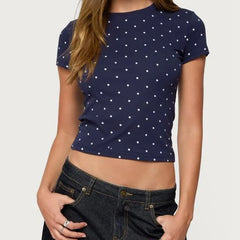 Person wearing a navy blue t-shirt with white polka dots and dark jeans