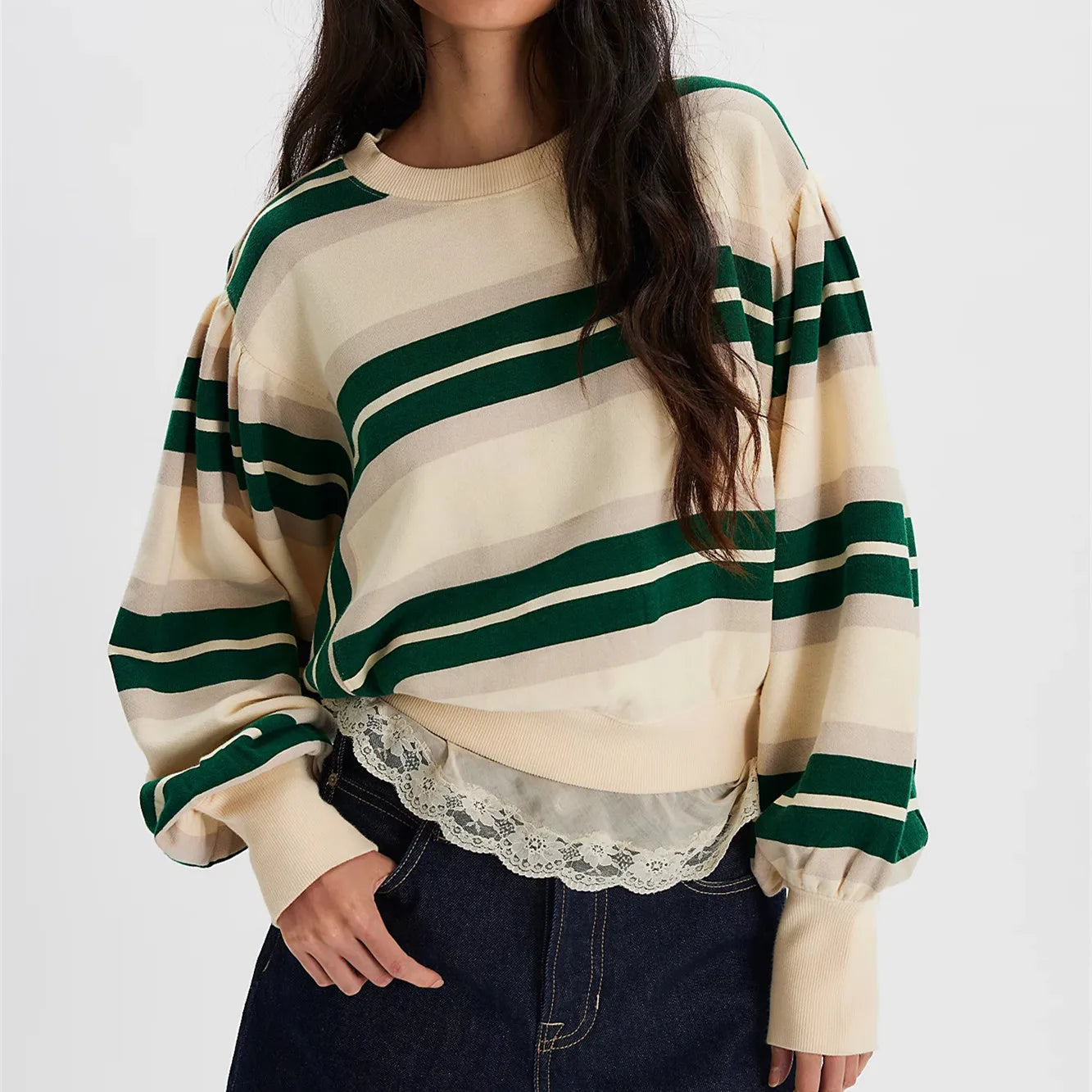 Person wearing a cream and green striped sweater with lace detail on a white background