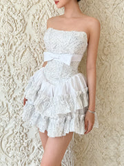 White lace dress with a belt against an ornate textured wall.