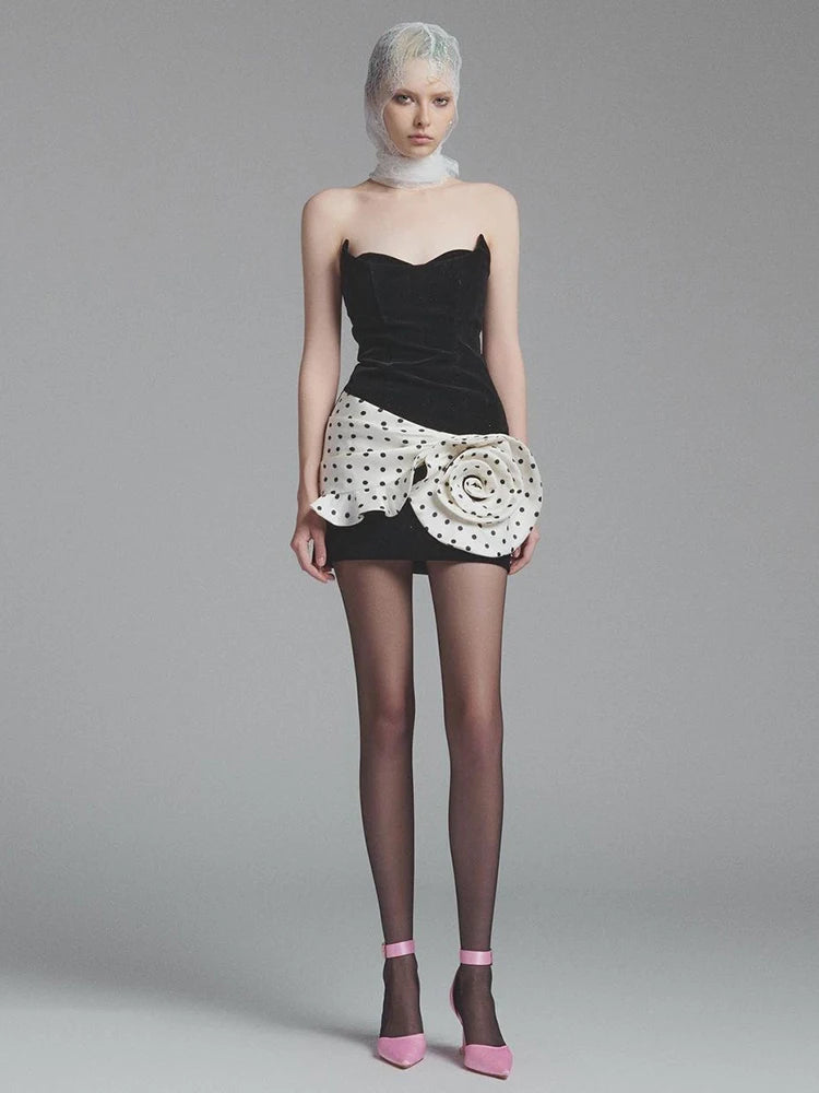 Model wearing a black strapless top and floral skirt with sheer stockings and pink shoes