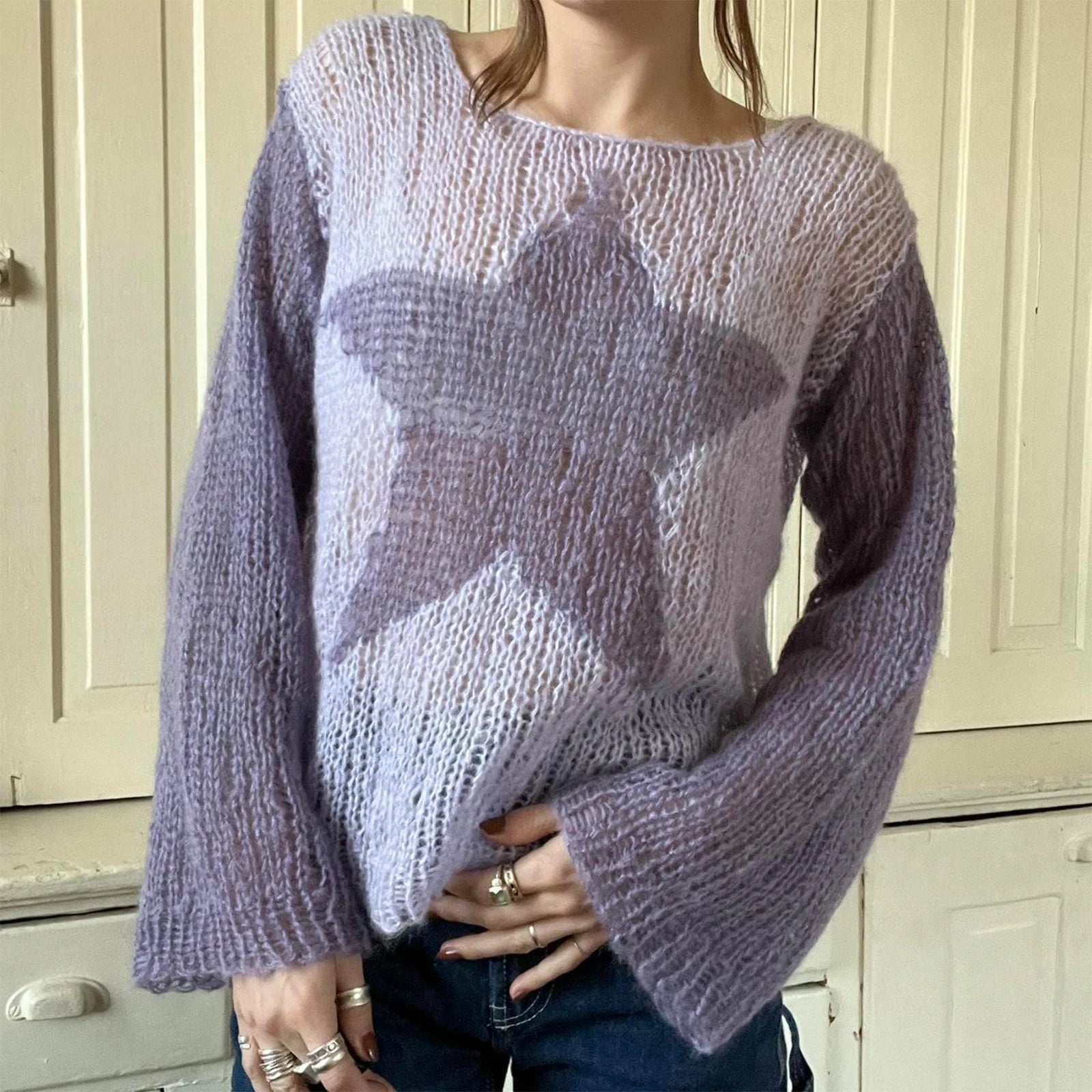 Person wearing a light purple sweater with star pattern in front of a white cabinet.