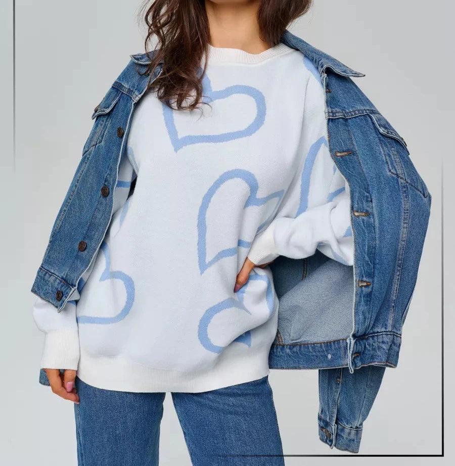Person wearing a white sweatshirt with blue heart designs and a denim jacket.