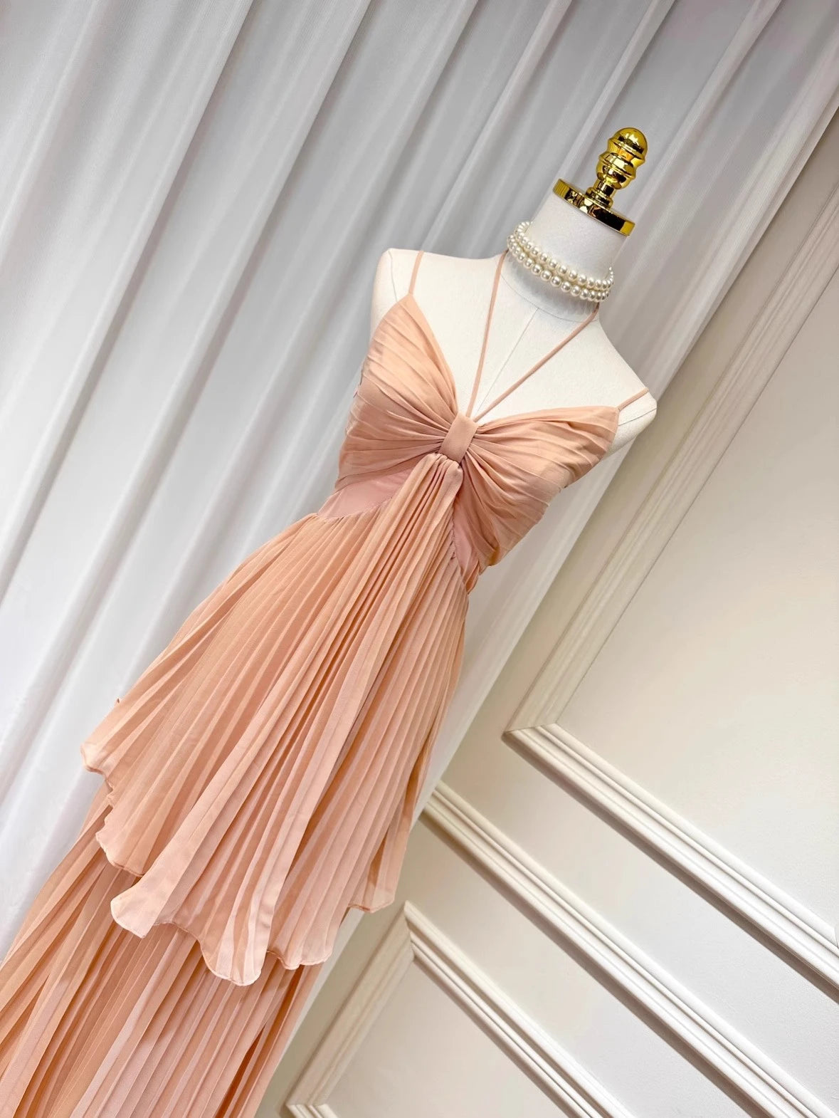 Pink dress on a mannequin against a white wall