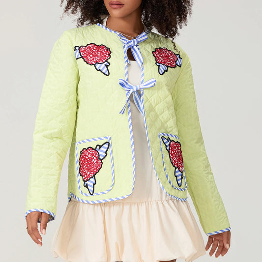 Light green quilted jacket with ice cream cone patches worn by a person on a plain background