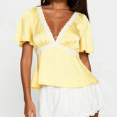 Model displaying a short lace trim flare short sleeve top with a V-neck.