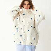 Woman wearing a cream-colored jacket with blue floral patterns on a white background