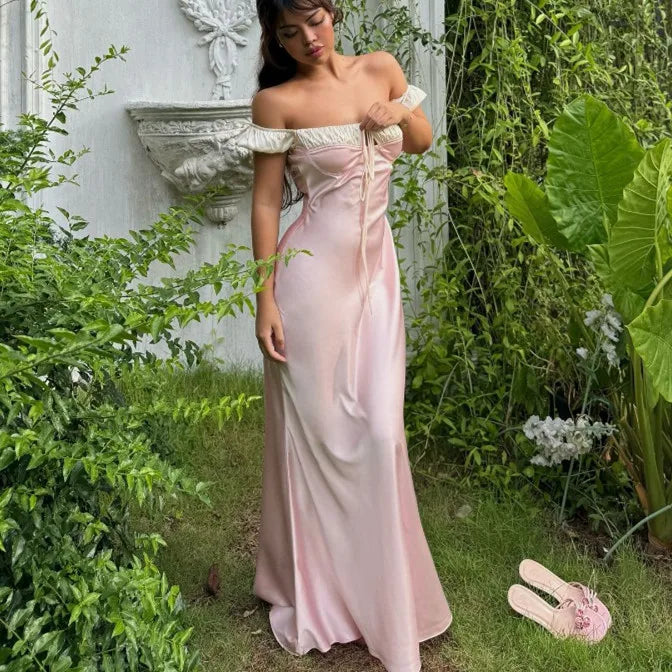Woman in a pink off-shoulder dress standing in a garden