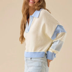 Woman wearing a cream sweater with blue accents