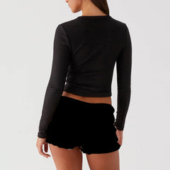 Model displaying a ribbed button long sleeve top with an O-neck and asymmetrical button detailing, showcasing its Y2K style.