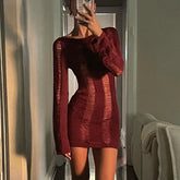 Person wearing a burgundy textured dress in a room with neutral decor.