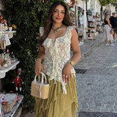 Woman holding a small handbag on a street with shops and people in the background