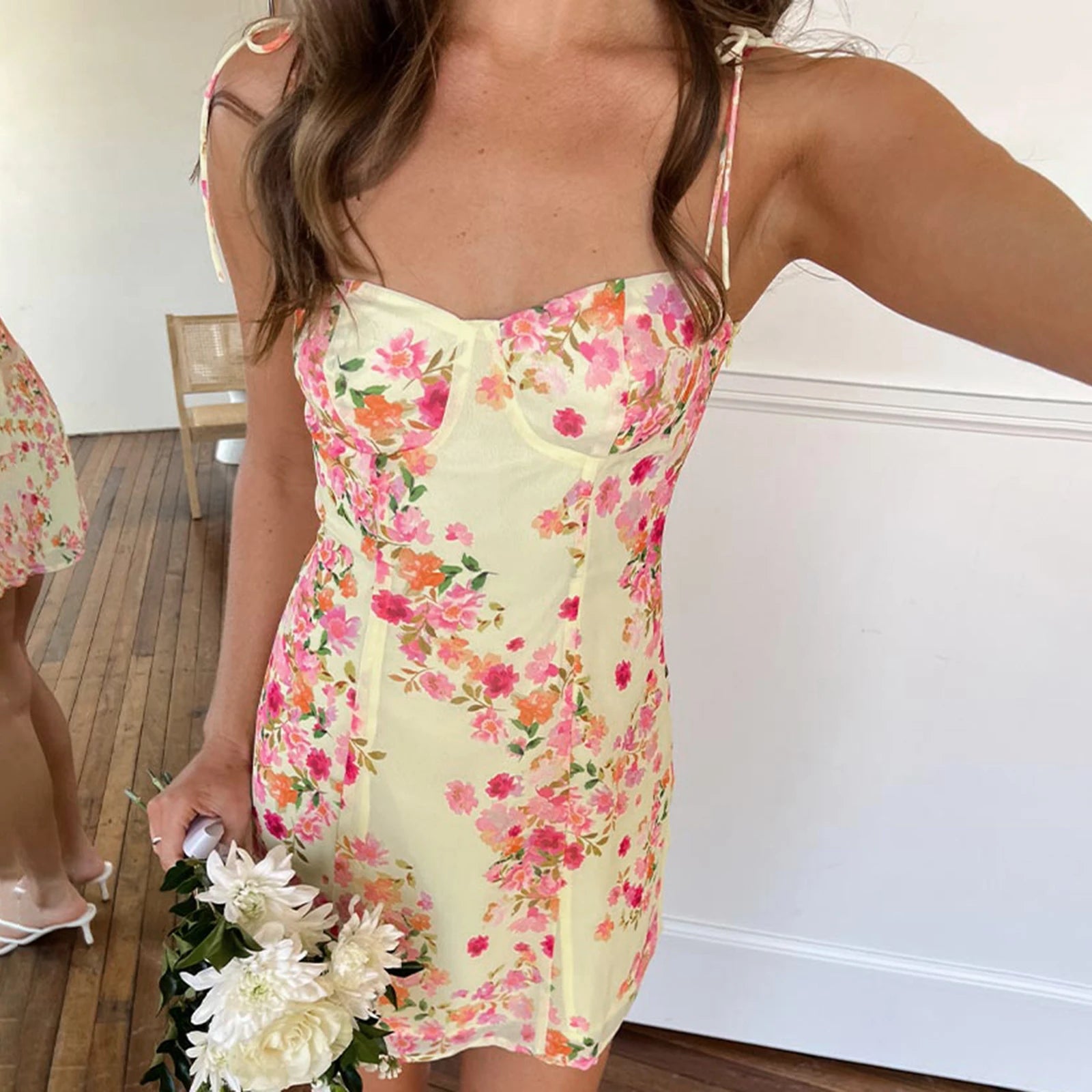 Woman in a floral dress holding flowers indoors