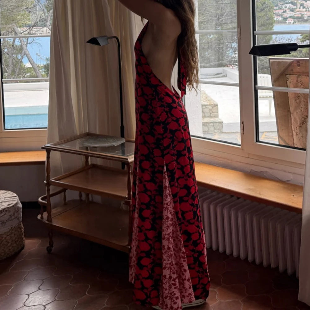 Woman in a red floral dress standing in a room with large windows and a pool view.