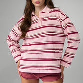 Person wearing a pink and red striped long-sleeve shirt and shorts on a gray background