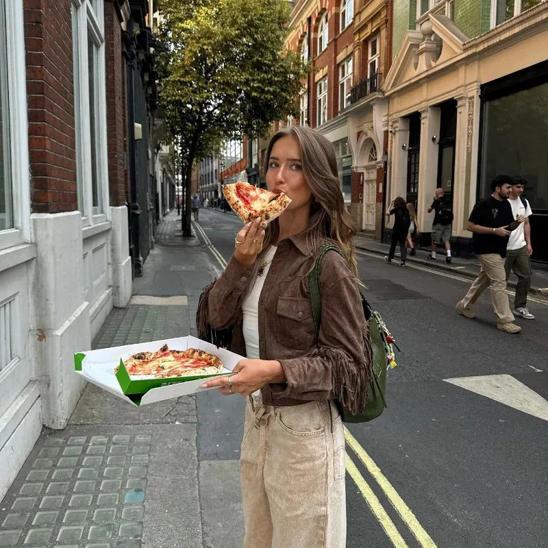 Woman eating pizza on a city street