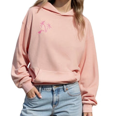 Person wearing a pink hoodie with palm tree design and light blue jeans