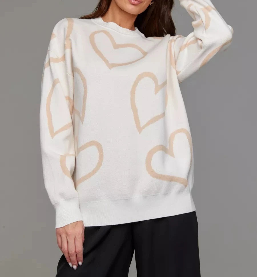 White sweater with beige heart patterns worn by a person