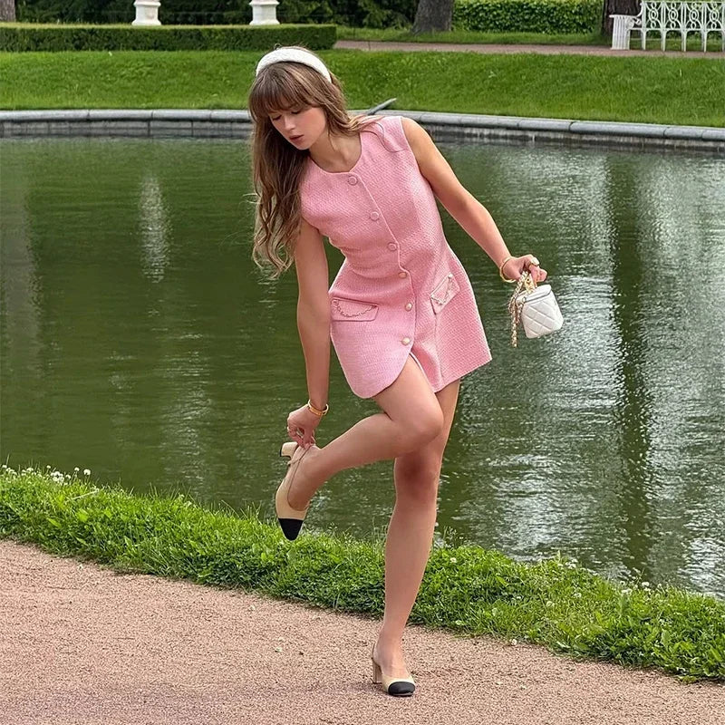 Woman in a pink dress standing by a pond in a park
