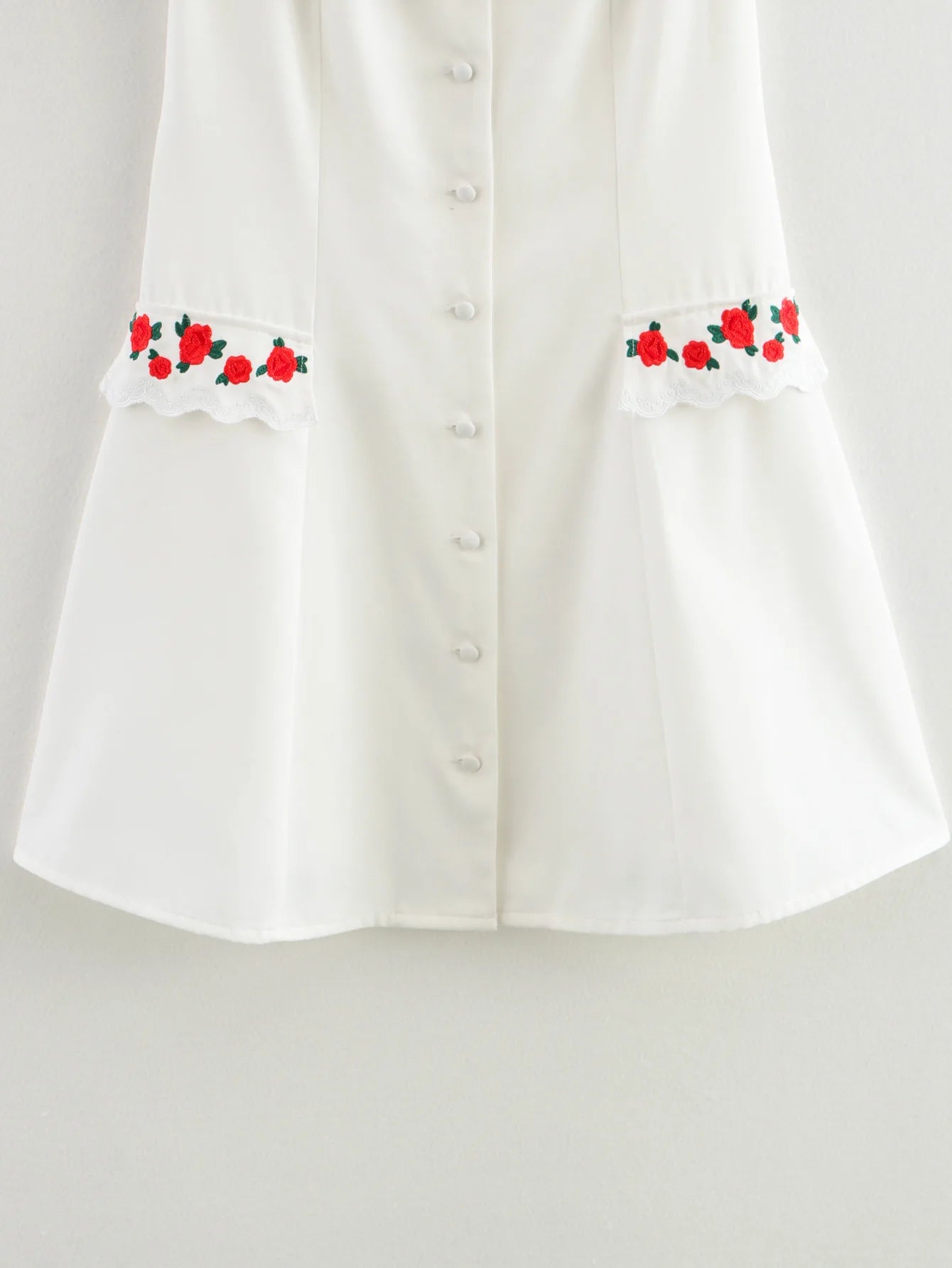 White blouse with floral embroidery on a light gray background