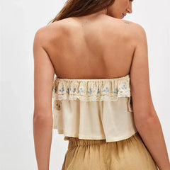 Woman wearing a beige strapless top with floral embroidery