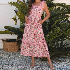Woman wearing a pink floral dress standing in front of green plants.