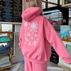 Person wearing a pink hoodie with a floral design in a store setting