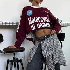 Person wearing a maroon sweatshirt with 'Motorcycle of Games' text, standing in a room with a white wall and black chair.