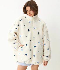 Woman wearing a cream-colored fleece jacket with blue patterns