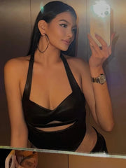 Woman taking a mirror selfie wearing a black halter top.