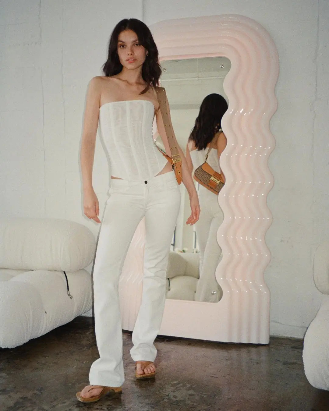 Woman in a white strapless outfit standing in front of an inflatable mirror.
