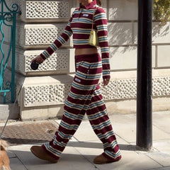 Person wearing a maroon and white striped outfit walking on a sidewalk.
