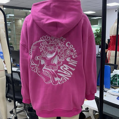 Pink hoodie with a skull design and text on a mannequin in an office setting