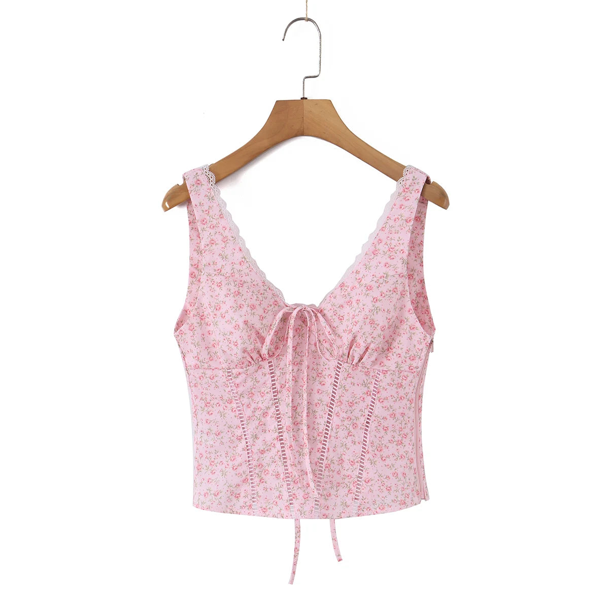 A pink floral sleeveless crop top with a lace-trimmed V-neckline, front tie detail, and lace-up side corset-style closures, hanging on a wooden hanger against a plain white background.