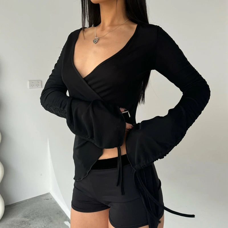 Person wearing a black long-sleeve top and shorts against a plain background