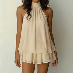 Beige halter neck dress worn by a model on a plain background