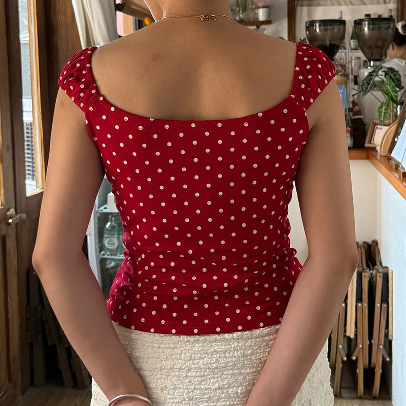 Person wearing a red polka dot top in an indoor setting