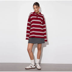 Person wearing a red and white striped sweater with a gray skirt on a plain background