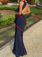 Woman in a navy blue evening gown with red accents walking outdoors.