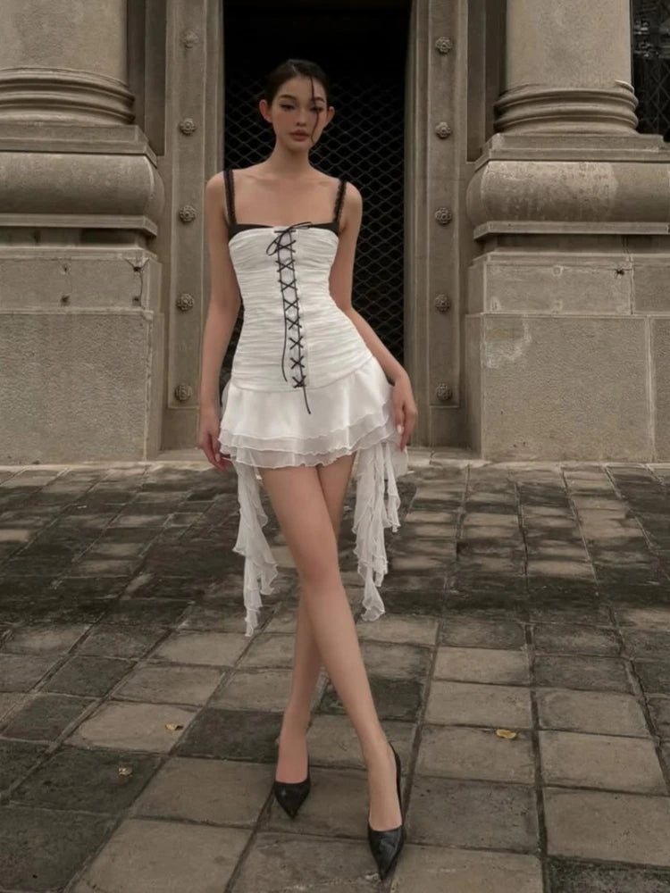 Woman in a black and white dress standing in front of a stone building.