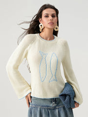 Woman wearing a cream sweater with blue tulip design against a white background